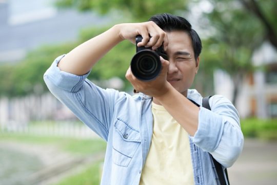 casually-dressed-asian-man-taking-photos-park.jpg